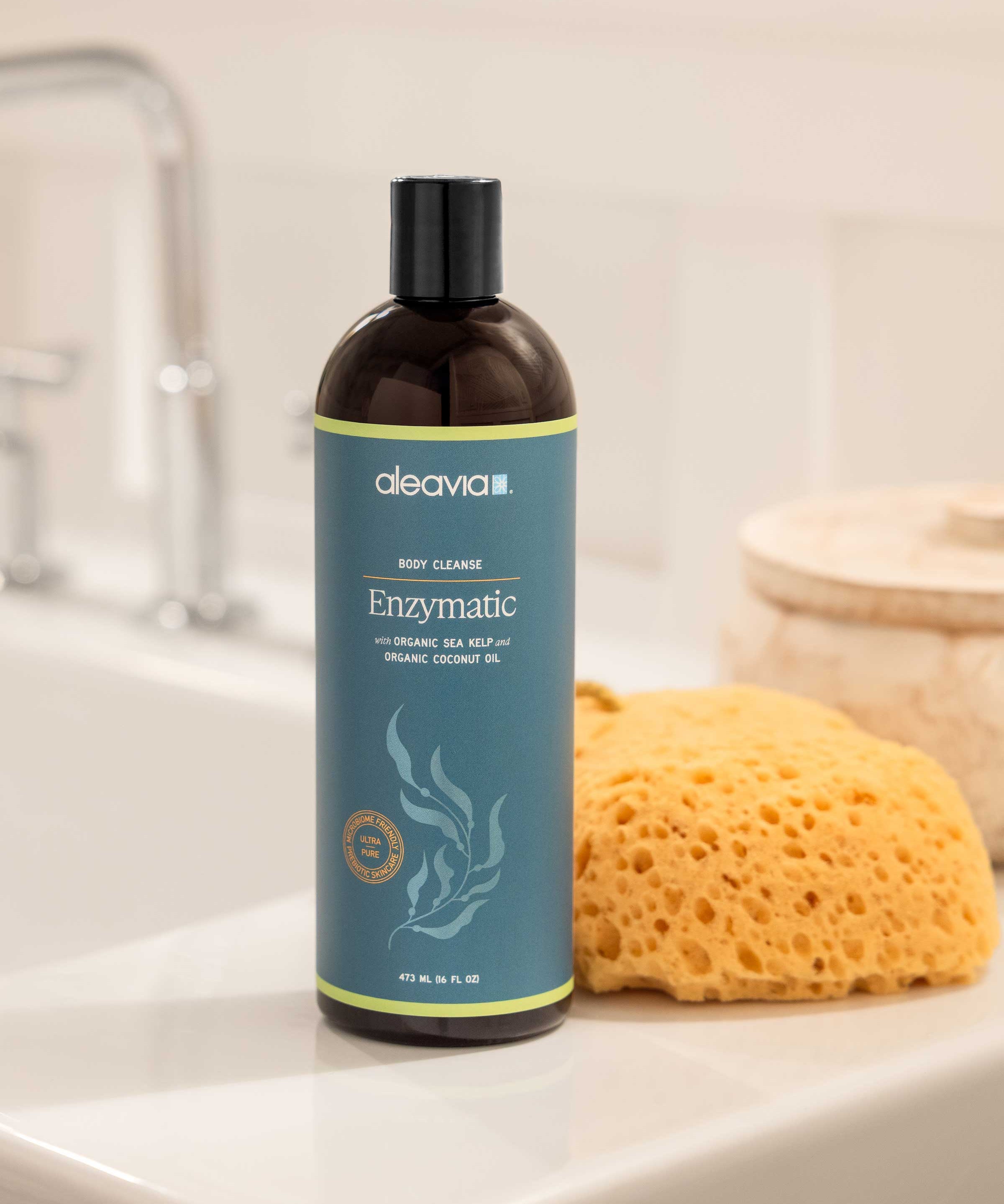 Bottle of aleavia Enzymatic body cleanse on a bathroom counter with a sponge.