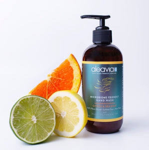 Bottle of Aleavia Microbiome Friendly Cleanser next to citrus fruits